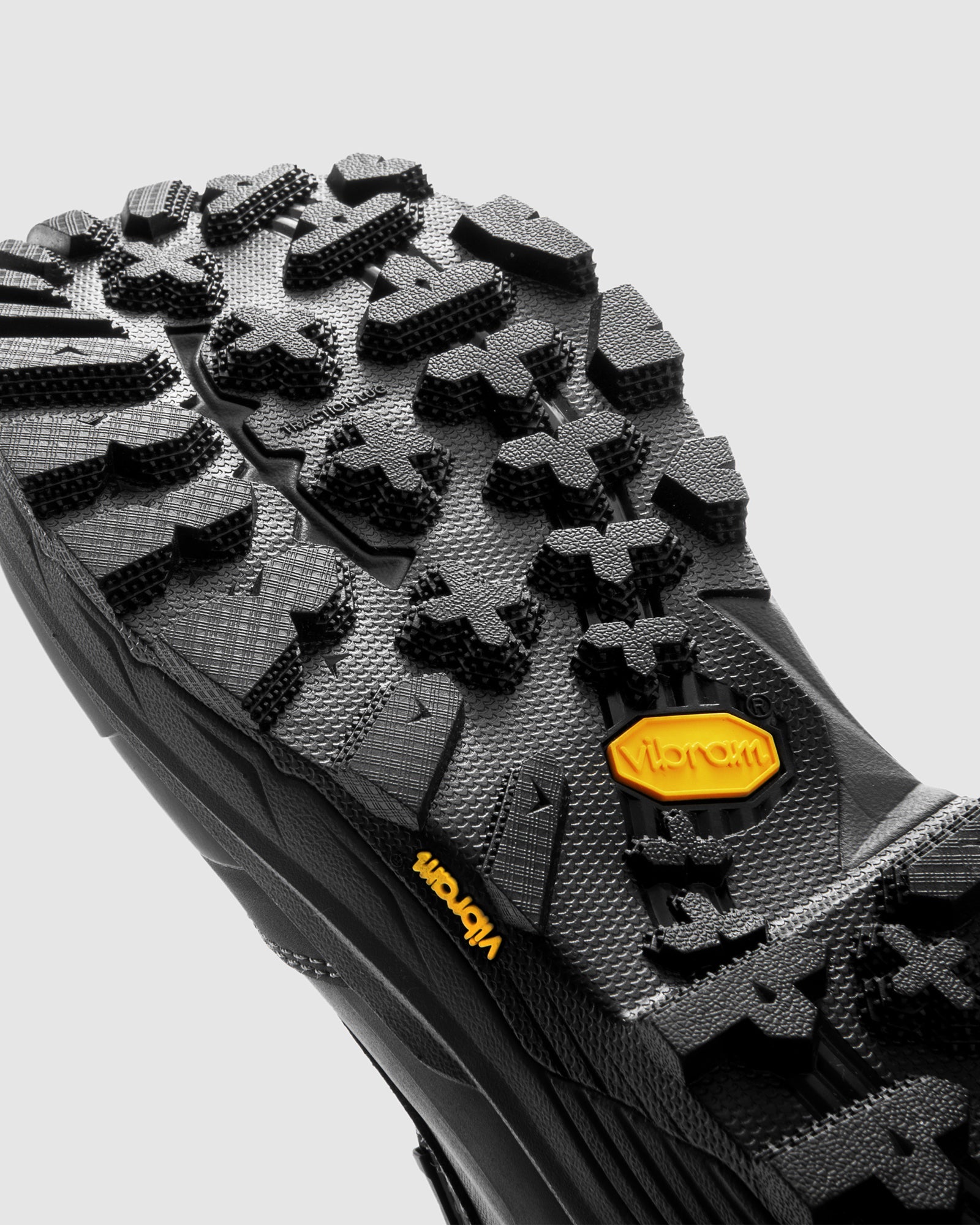 Close-up of a black hiking boot sole with Vibram branding on a light gray background